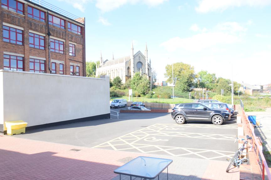 A meeting centre with an outdoor parking area, accessible spaces, and a view of a church at Humanitarian Academy for Development.