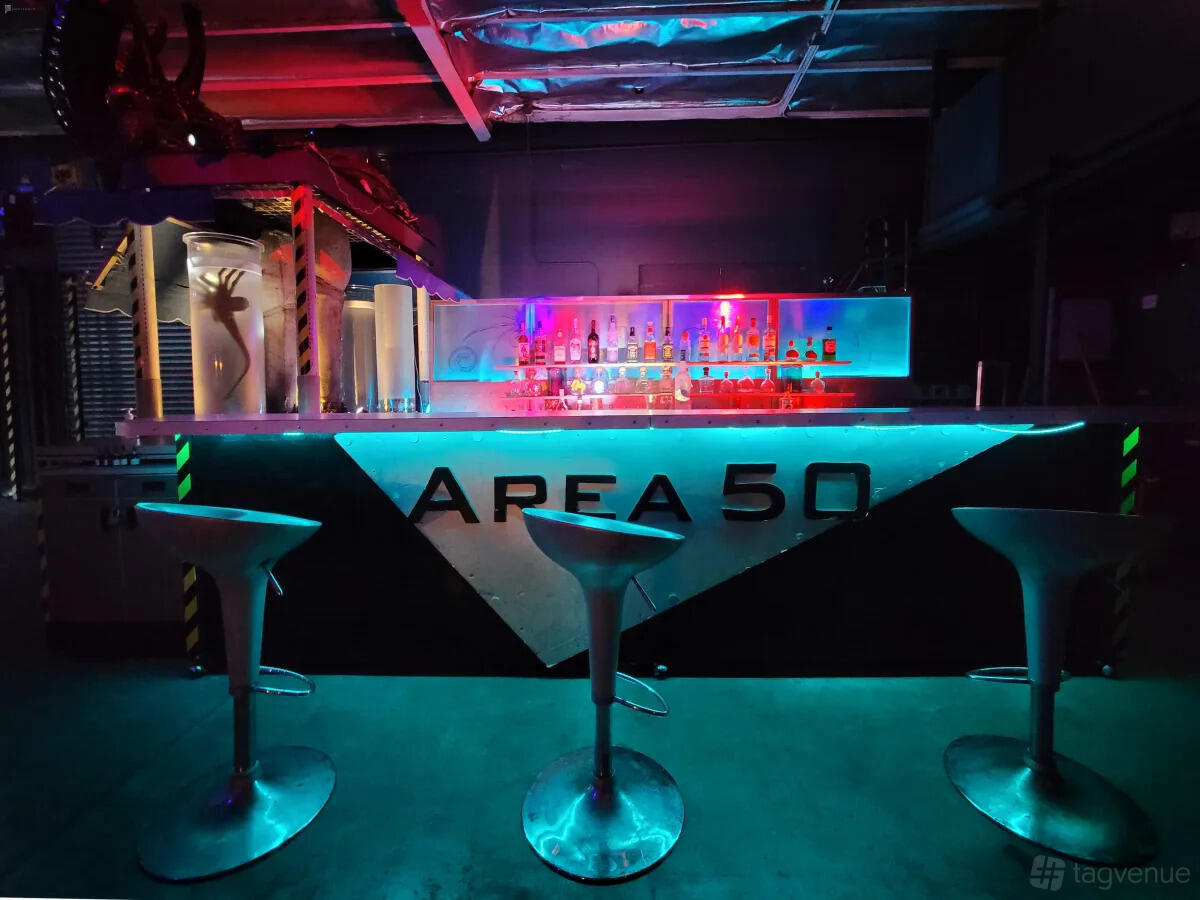 A photo studio with neon-lit bar counter, futuristic stools, and LED lighting at Cosmic Cube Creative Studio.