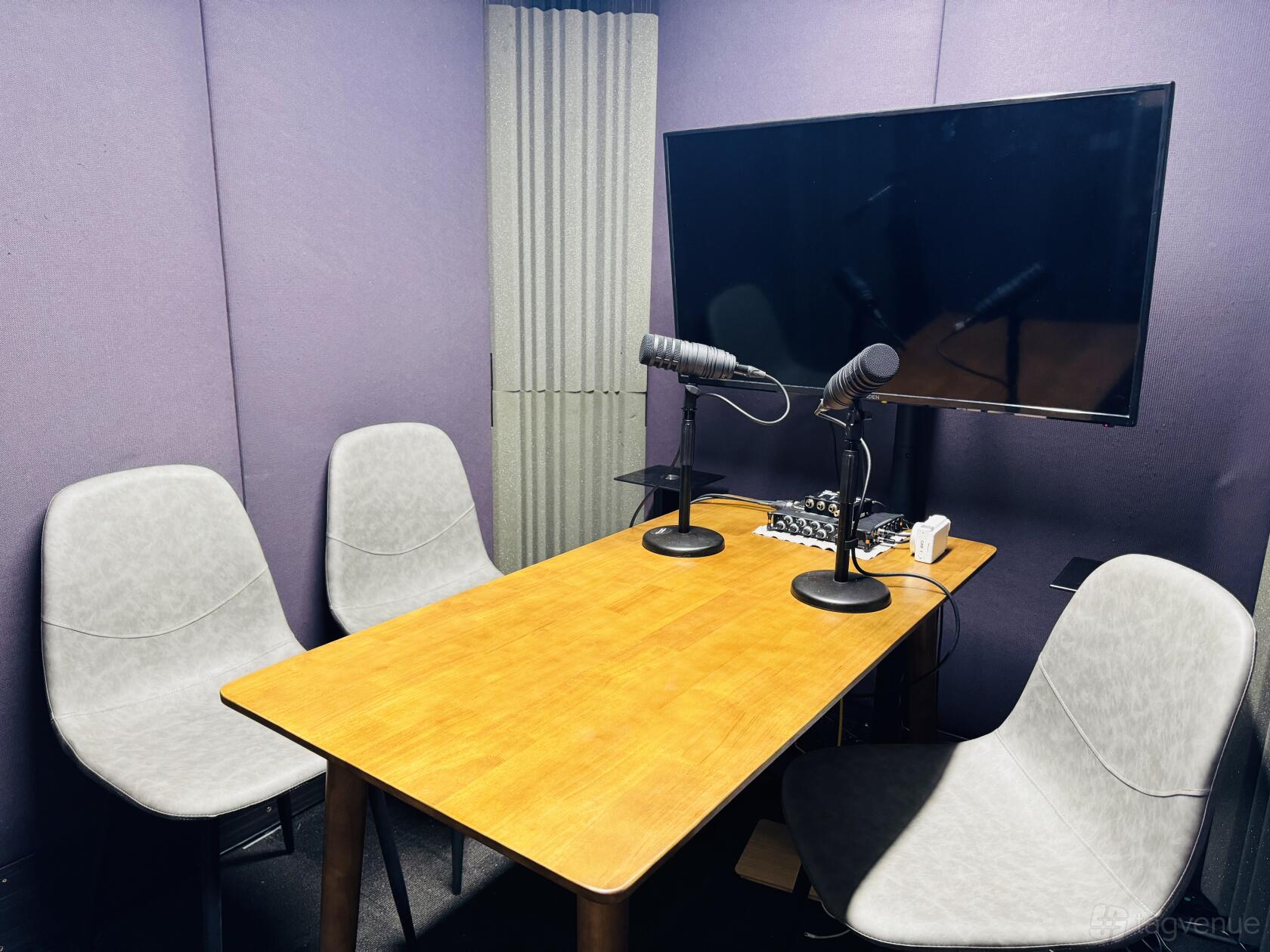 A recording studio with purple soundproof walls, podcast microphones, and a wood table at Echidna Audio.