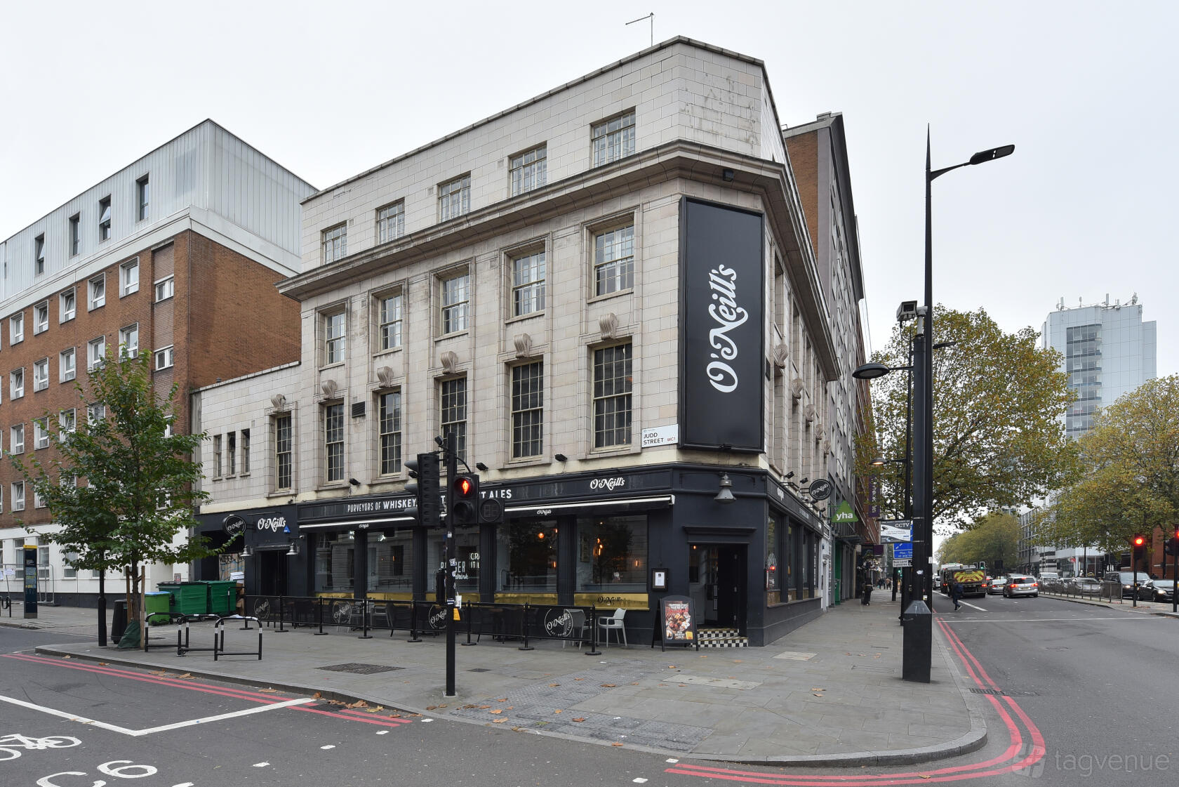 A street corner pub with large windows, outdoor seating, and prominent O'Neill's signage at O'Neill's Kings Cross.