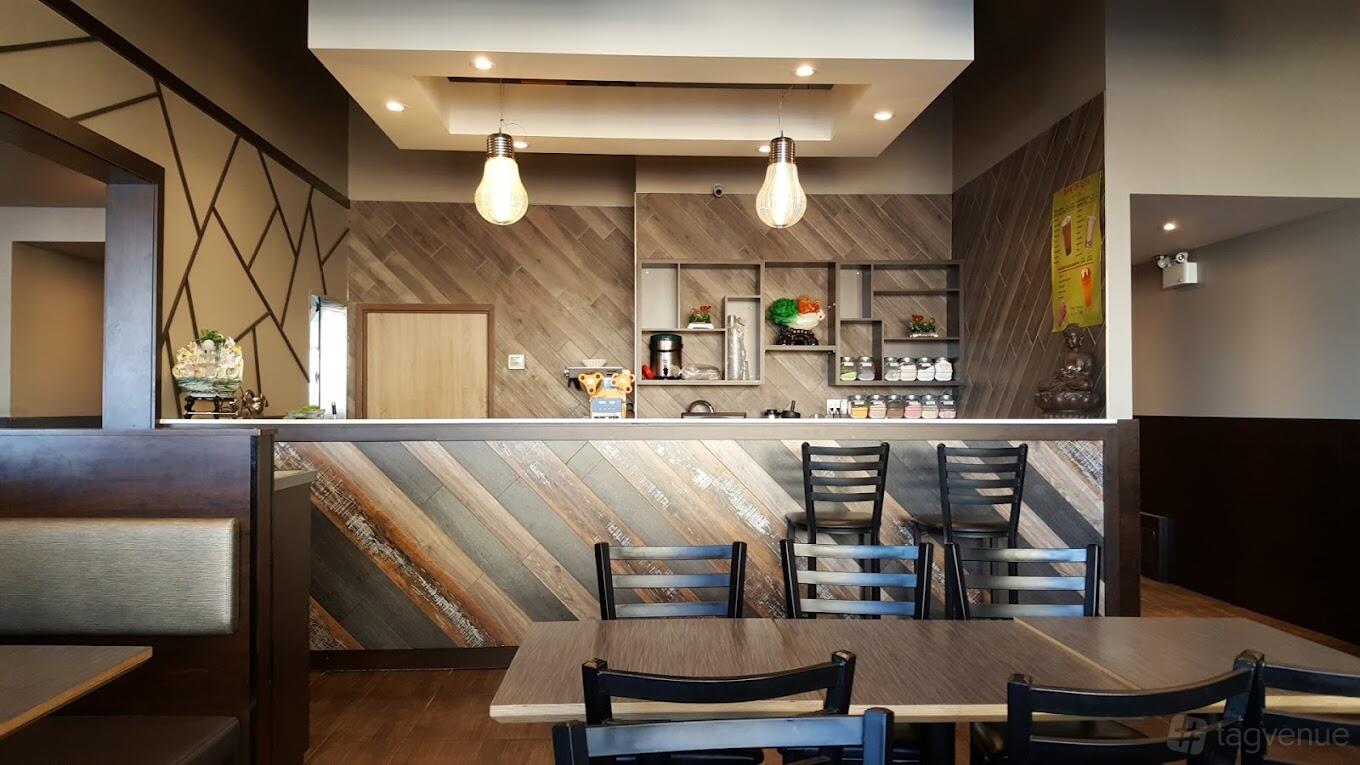 A dining room with wood-paneled walls, hanging pendant lights, and black chairs at Wok Of Asia.