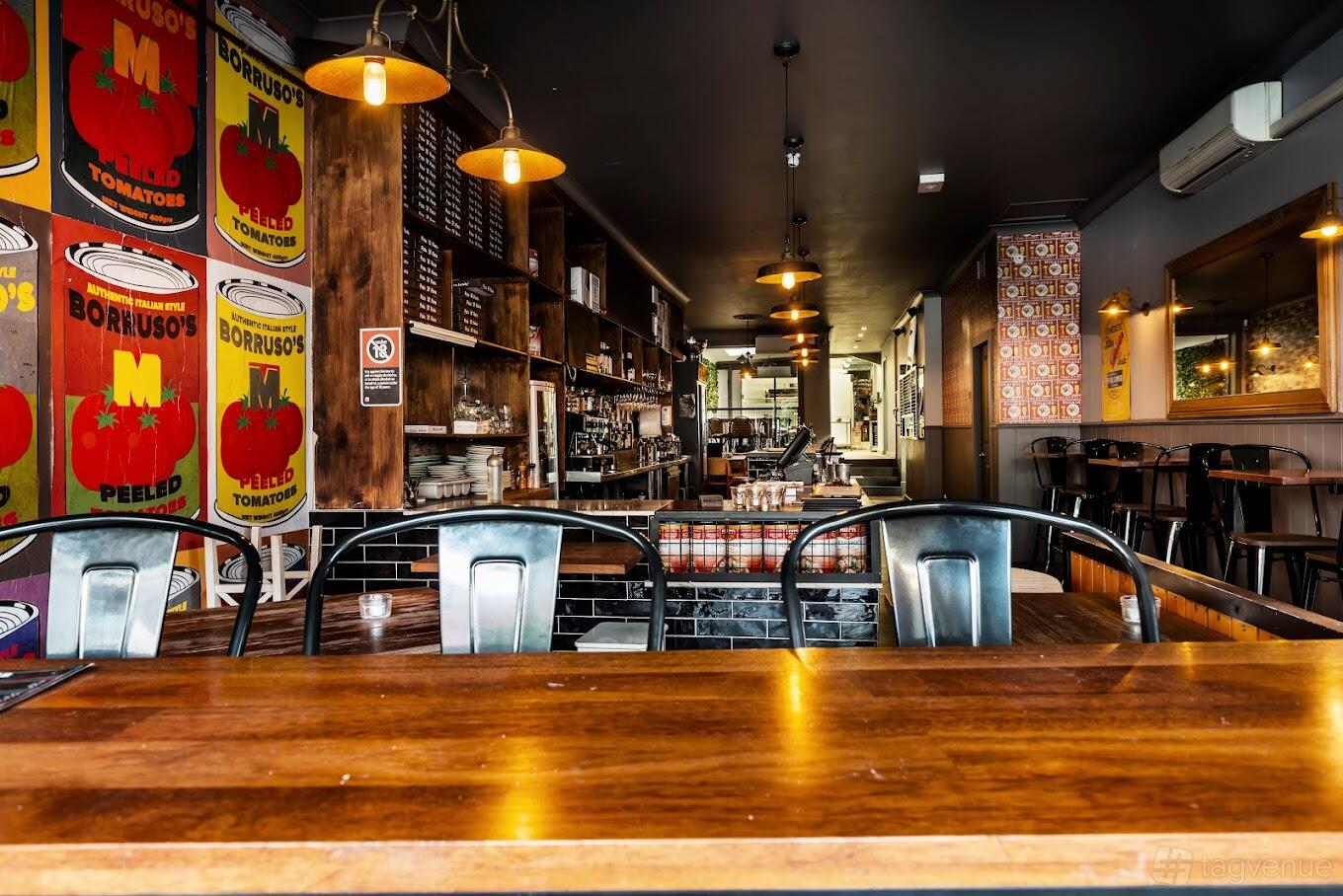 An event space in a restaurant with wood tables, industrial chairs, and vintage tomato can wall art at Borruso's Crows Nest.