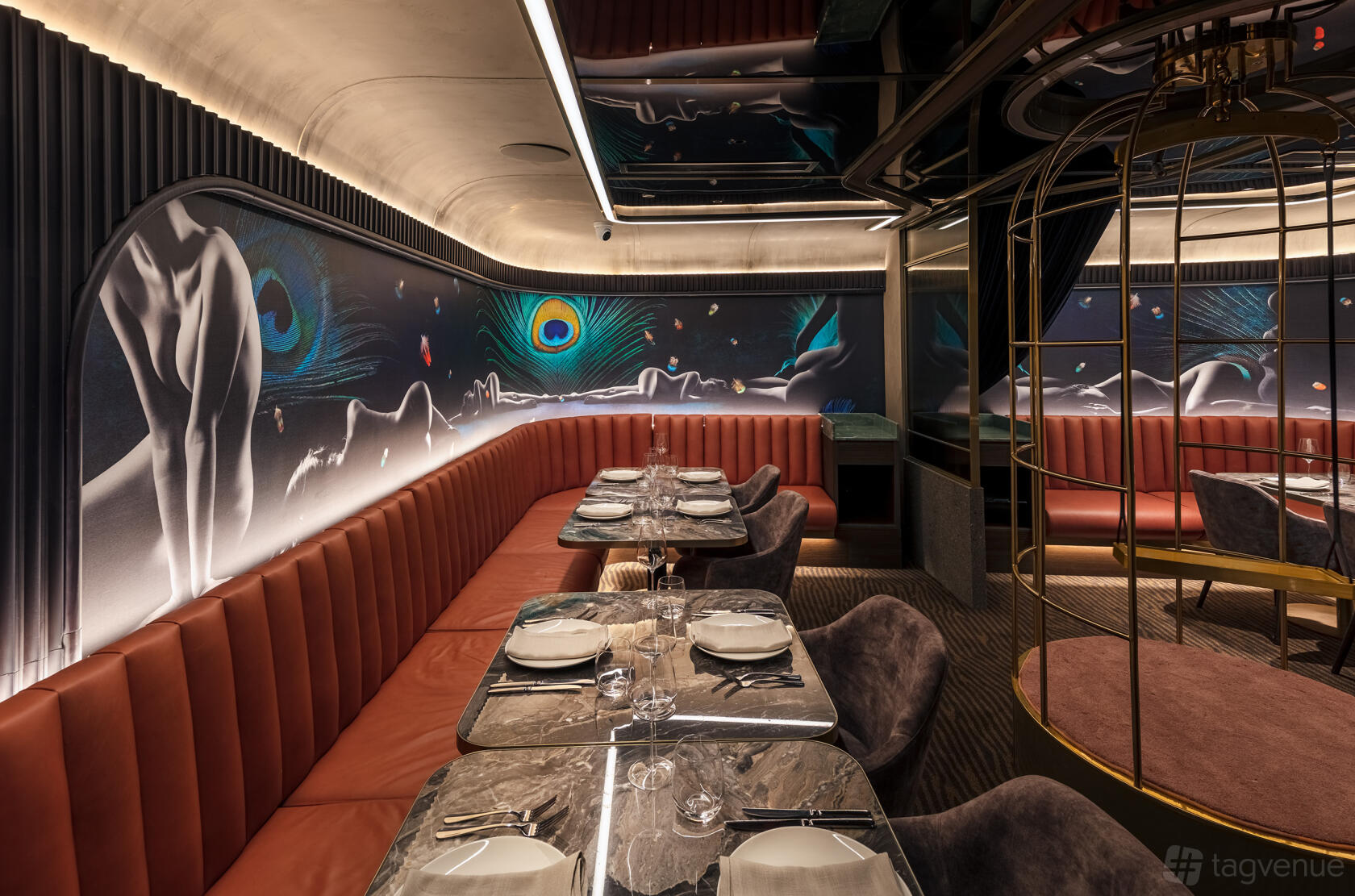 A cafe with mural walls, leather banquette seating, and marble-topped tables set for dining at The aVenue.
