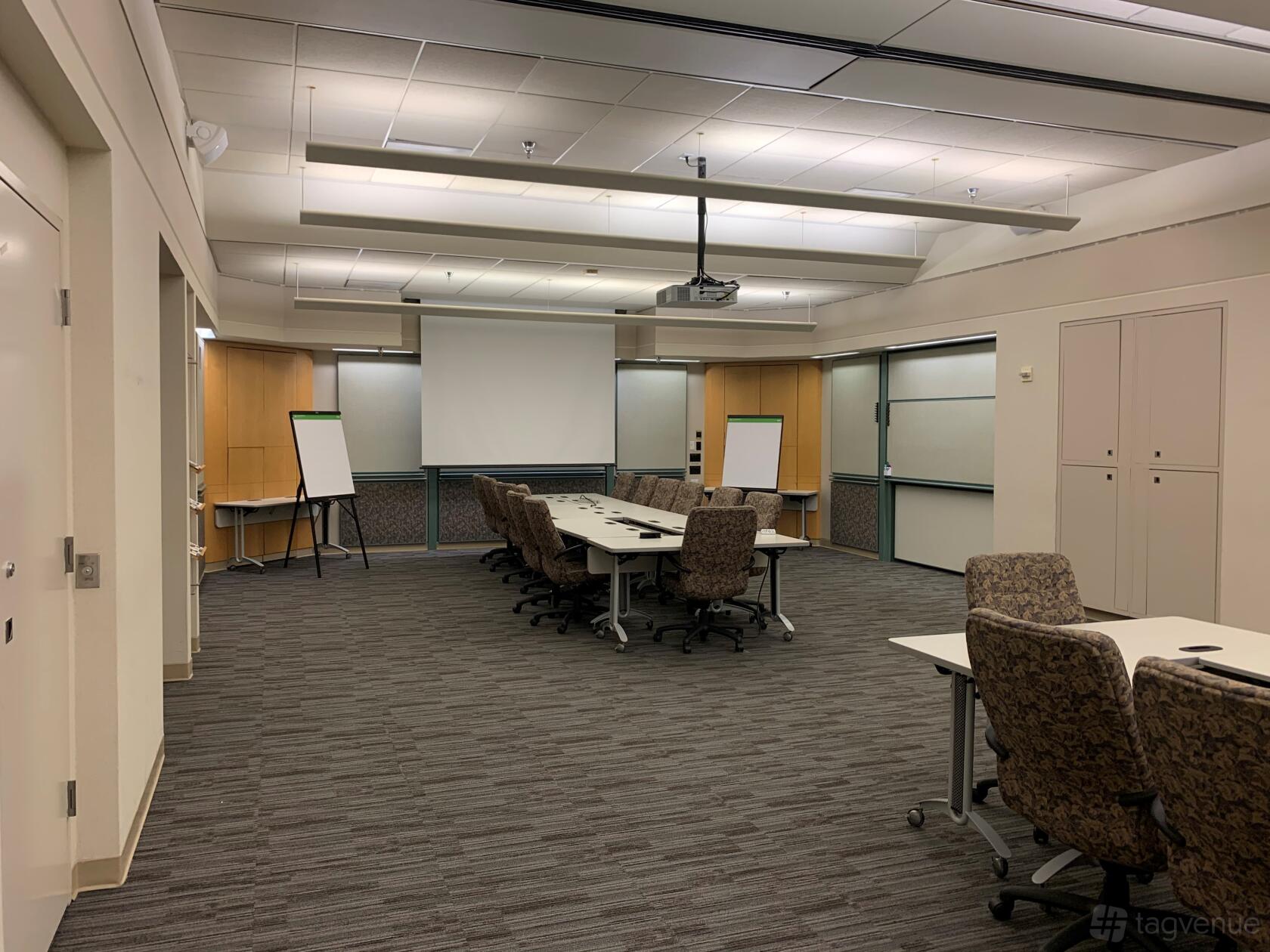 A conference centre training room with modular tables, rolling chairs, whiteboards, and a projector at AMA's SF Executive Conference Center.