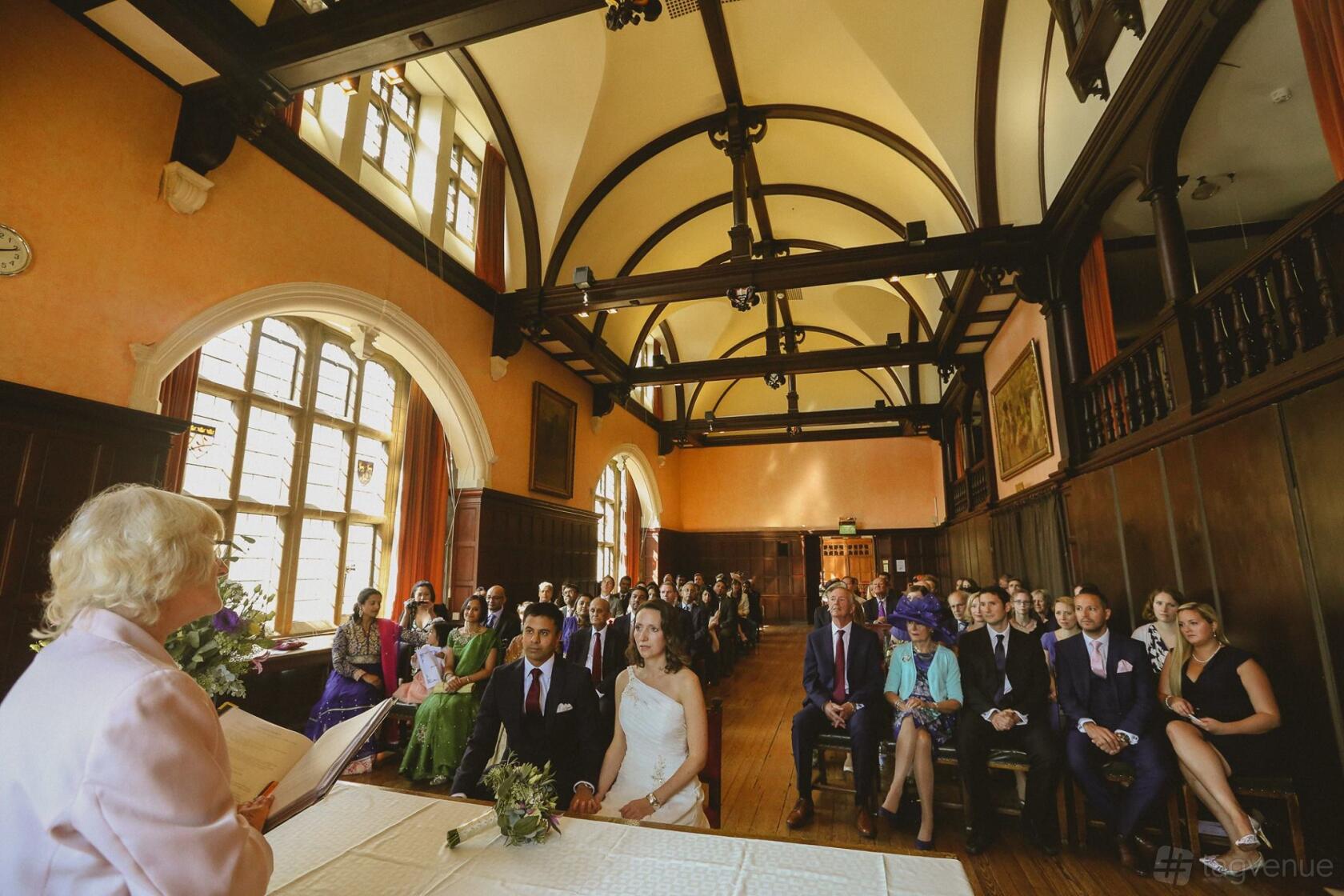 A hall with vaulted wooden beams, large arched windows, and wood paneling at Oxford Town Hall, The Old Library.