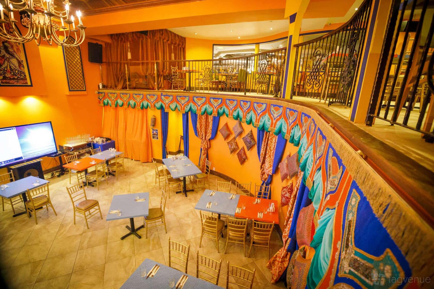 A restaurant with colorful draped fabrics, vibrant wall patterns, chandeliers, and scattered tables at Chaihana.