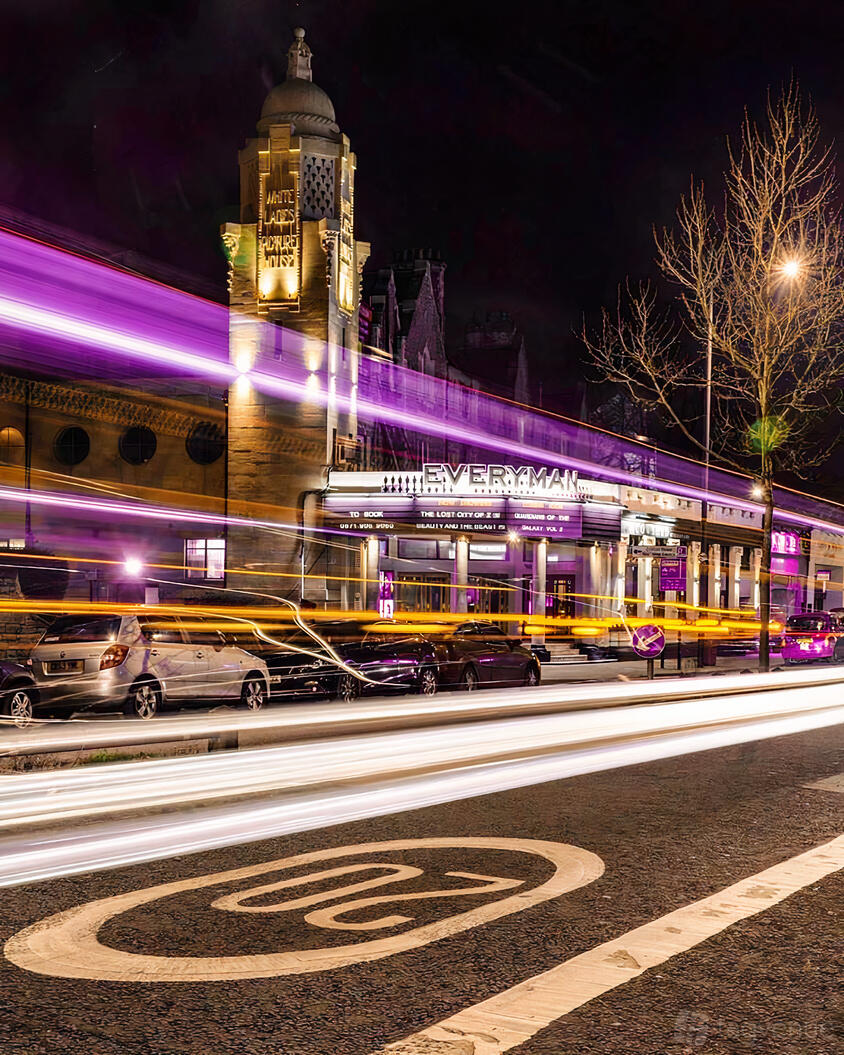 A cinema with illuminated marquee, art deco facade, and street light trails in front of Everyman Bristol.