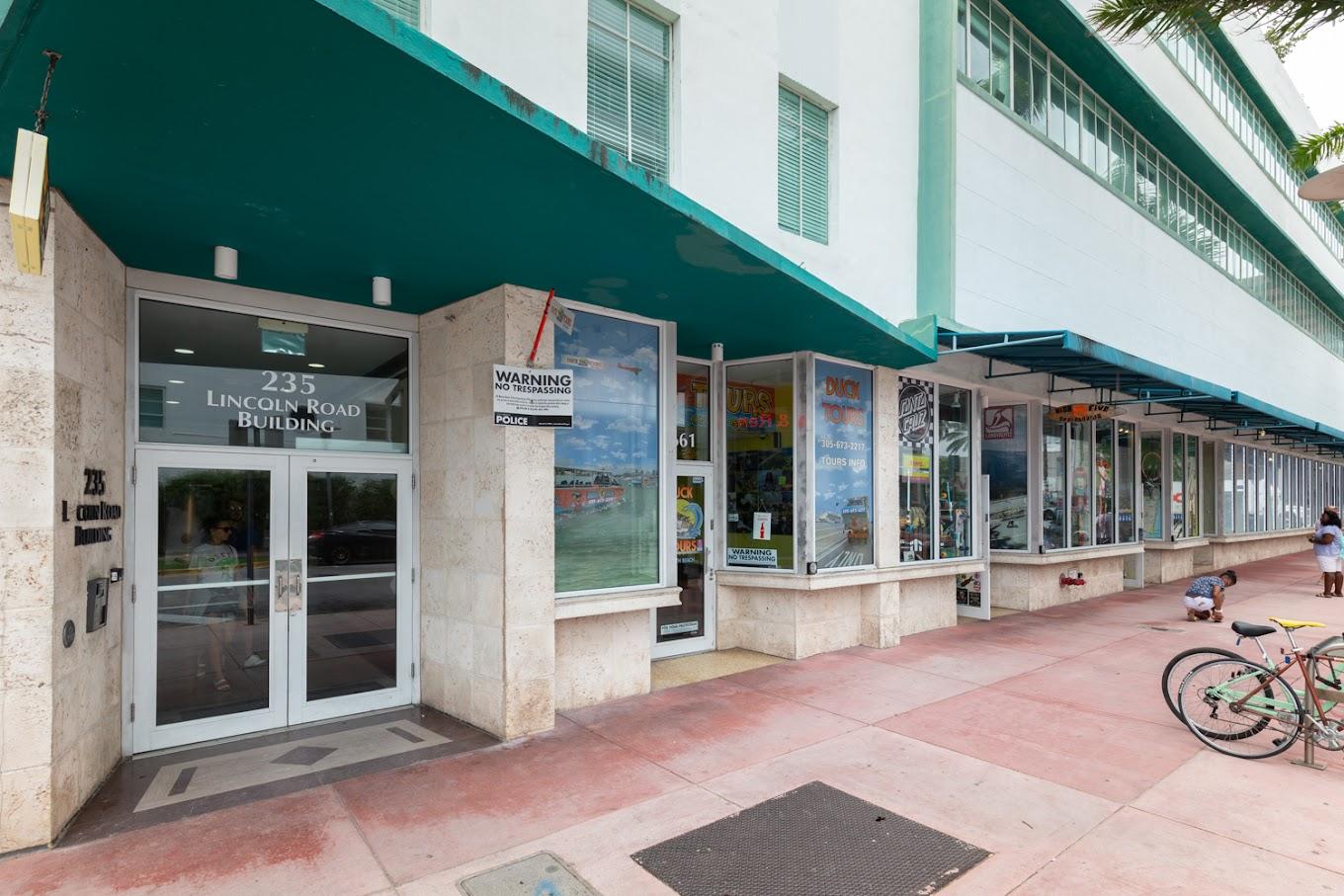 A street-level bar entrance with glass doors and large storefront windows at South Beach Room Escape Bar & Rooftop.