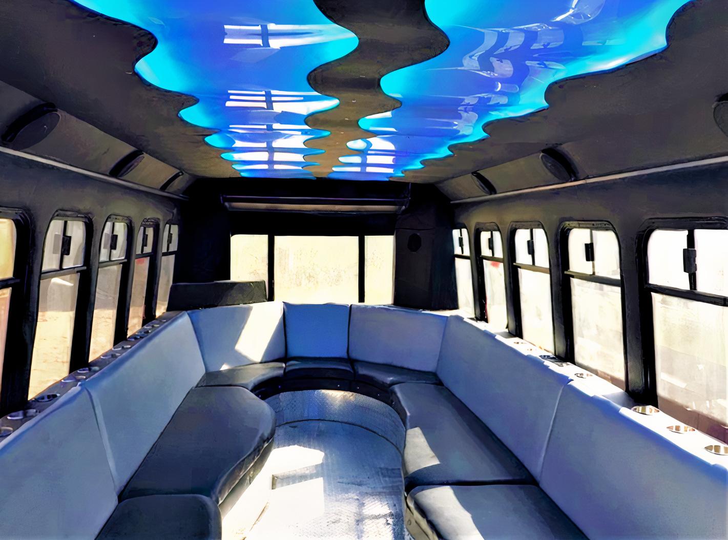 A party bus with wraparound leather seating and a ceiling lit by blue accent lights at ThunderDome Party Bus.