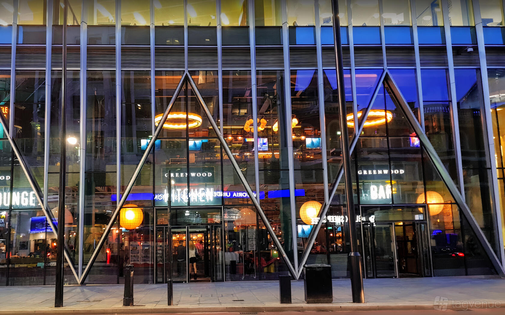 A bar with floor-to-ceiling glass windows, geometric frames, and warm pendant lighting at Greenwood.