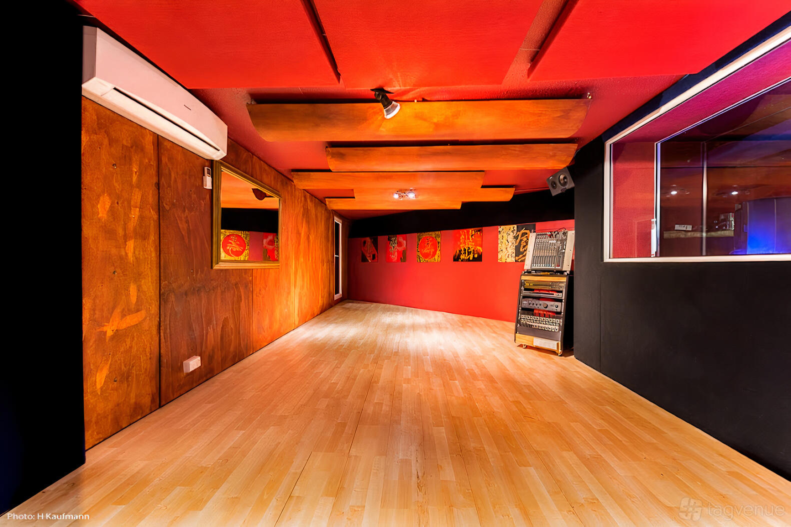 A rehearsal studio with wood-paneled walls, acoustic ceiling panels, and a light wood floor at Jaminajar Music Production.
