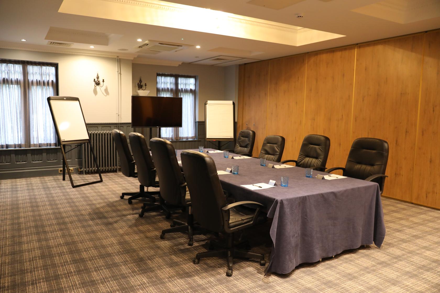 An event space with a boardroom table, executive chairs, and flip charts at Stanhill Court Hotel.