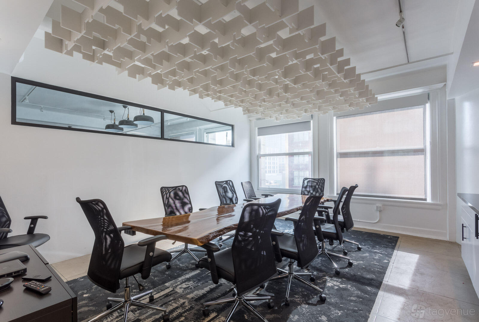 A meeting room with a large wood conference table, ergonomic chairs, and ceiling acoustic panels at The Collection.