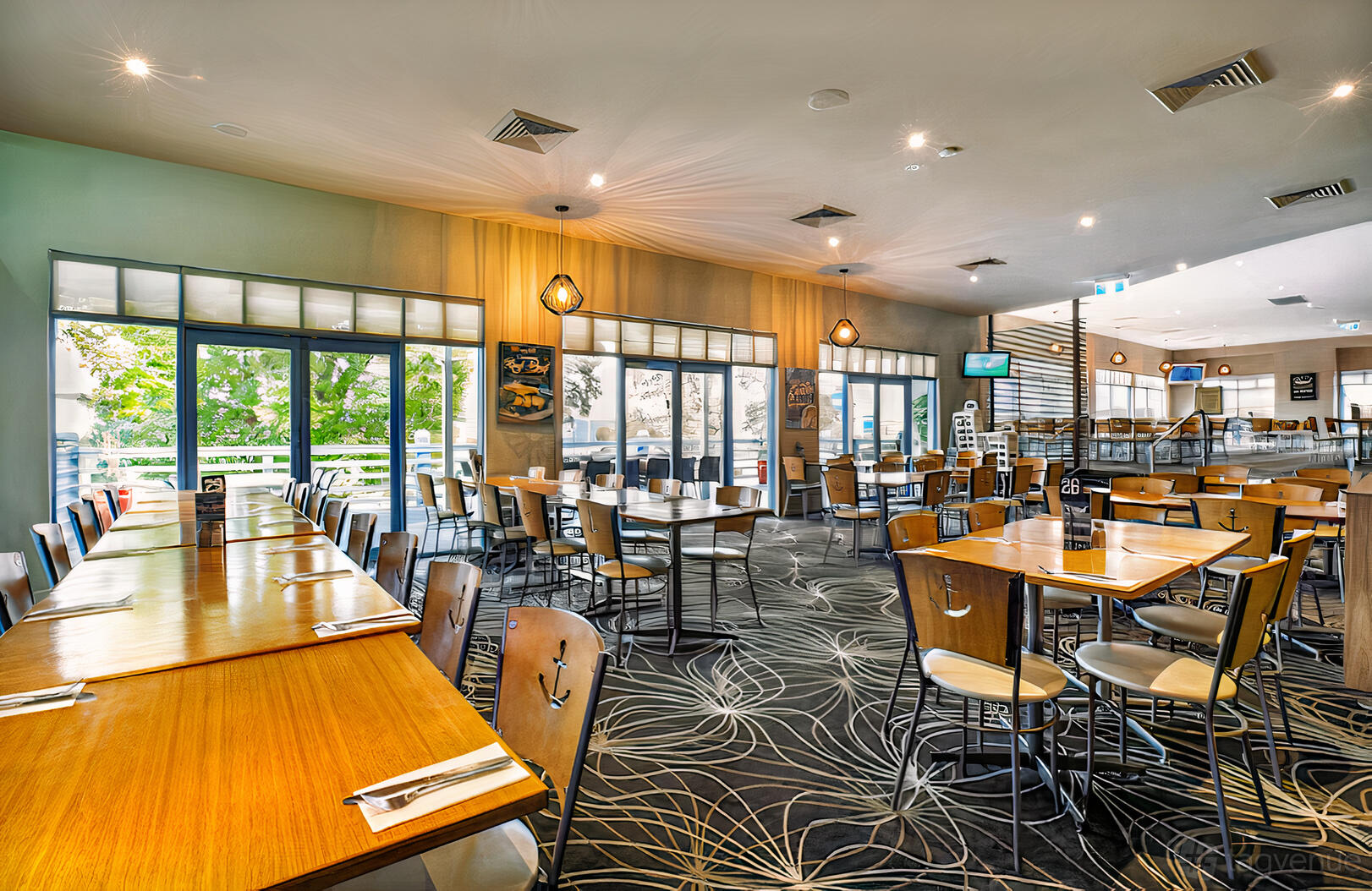 A pub dining area with wooden tables, patterned carpet, and large windows at Vale Hotel.