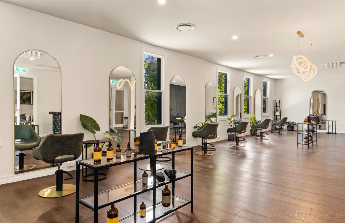 An event venue with arched mirrors, styling chairs, and wooden floors at Privé Hair Organics.