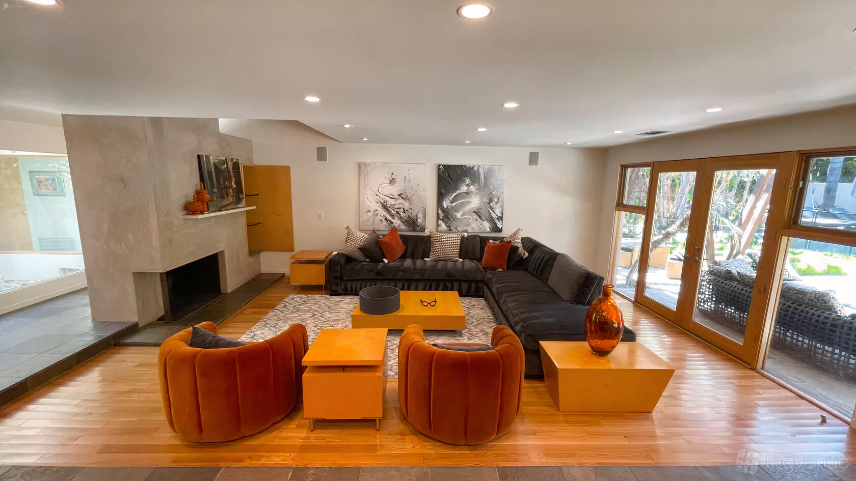 A house with a spacious living area, large sectional sofa, orange armchairs, and glass doors at Modern Encino Sanctuary.