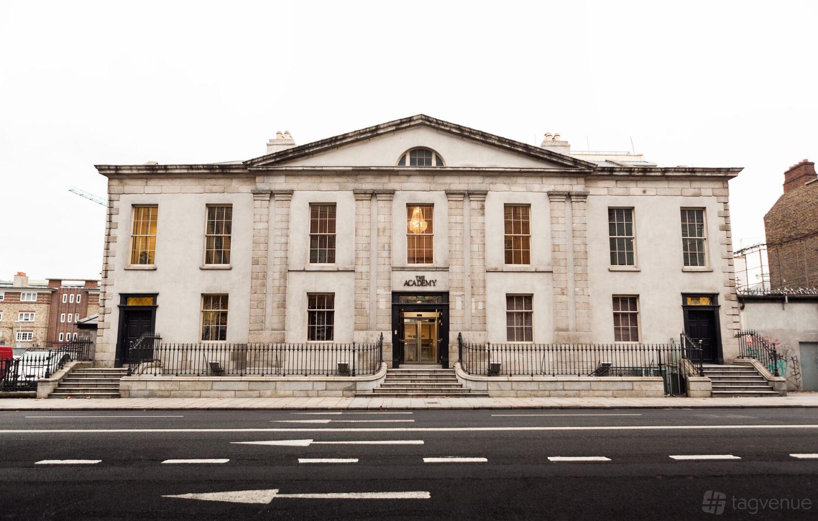 A coworking space in a neoclassical stone building with large windows and a columned entrance at Huckletree D2.