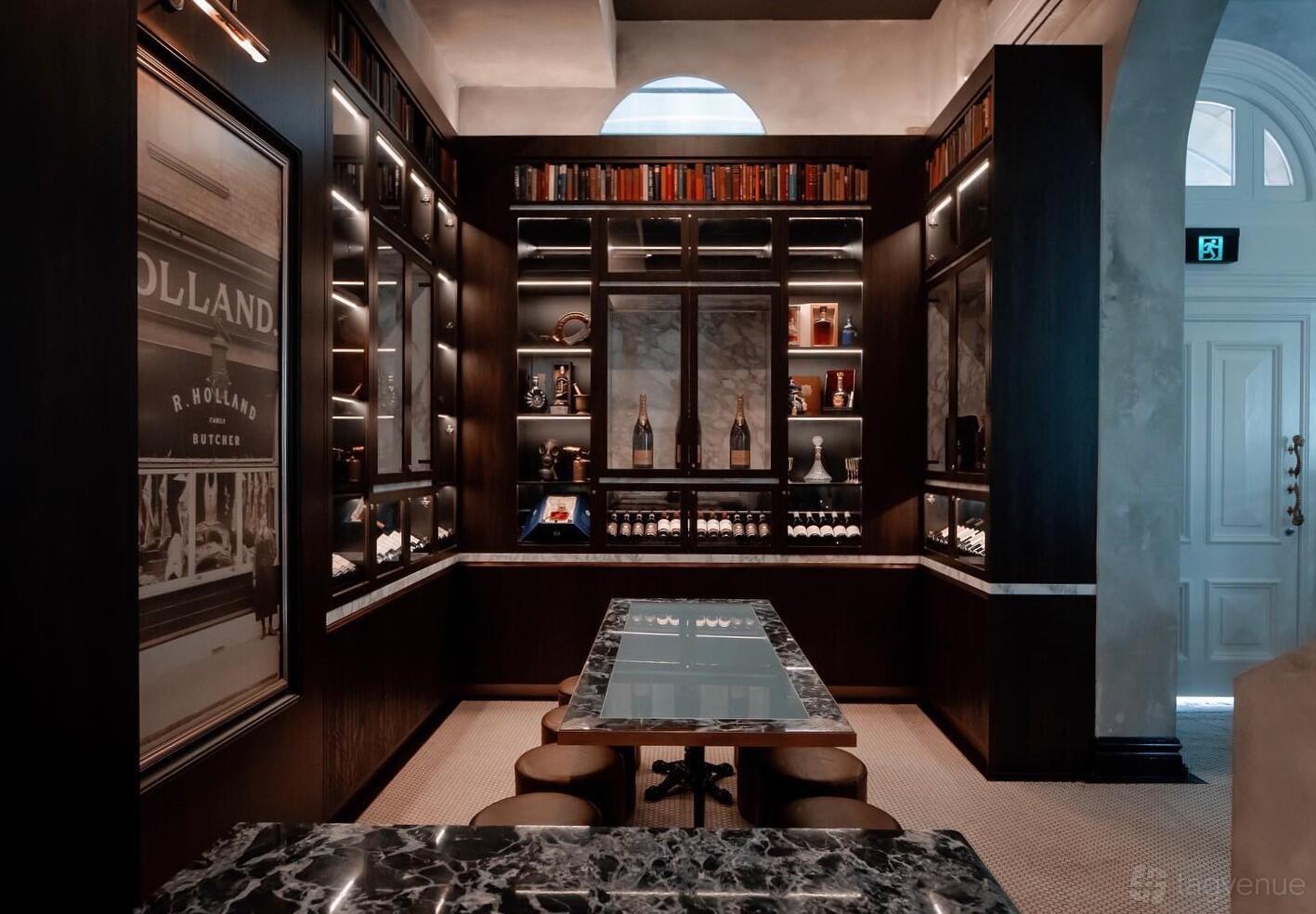 A cocktail bar event space with marble tables, leather stools, and built-in bookshelves at The Cat's Meow.