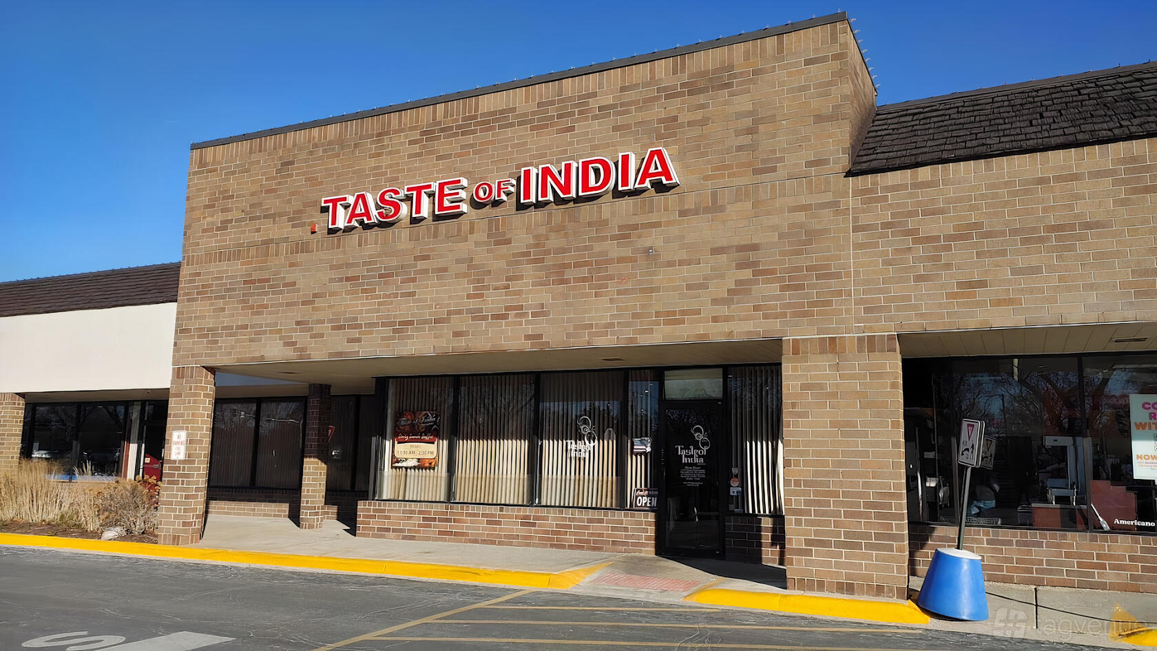 A restaurant with a brick exterior, large windows, and a red sign reading 'Taste of India Restaurant- Banquet & Catering'.