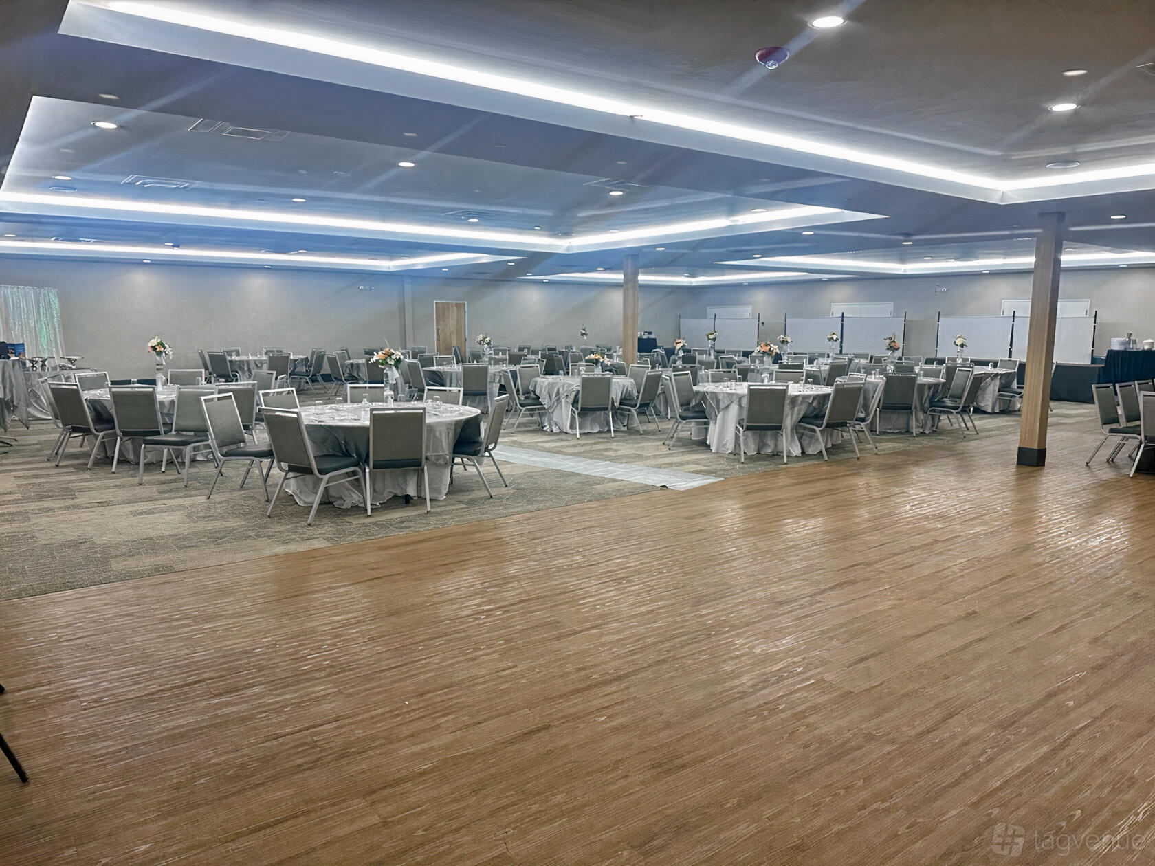 An event venue hall with round tables, silver chairs, and neutral-toned walls at Vansh Event Center.
