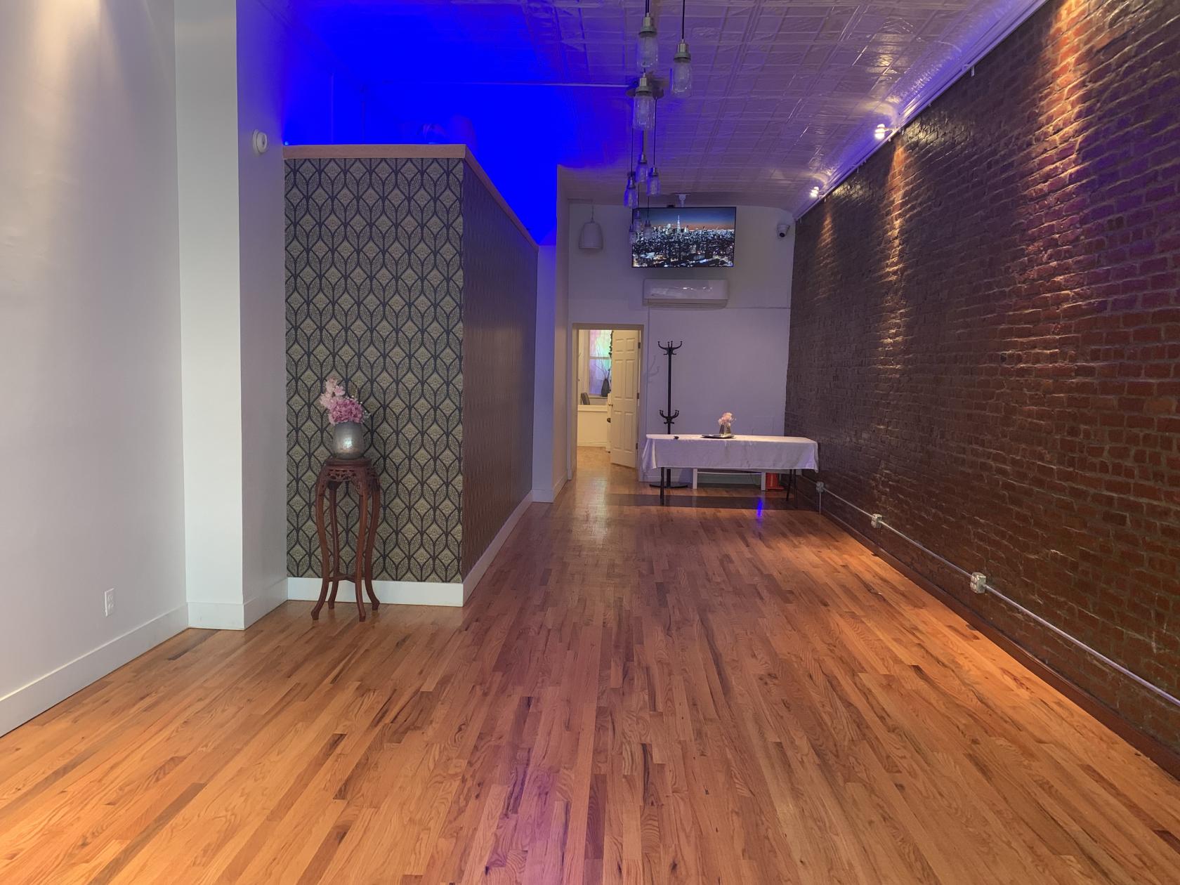 An event venue with exposed brick walls, hardwood floors, and a patterned accent partition at H I D D E N.