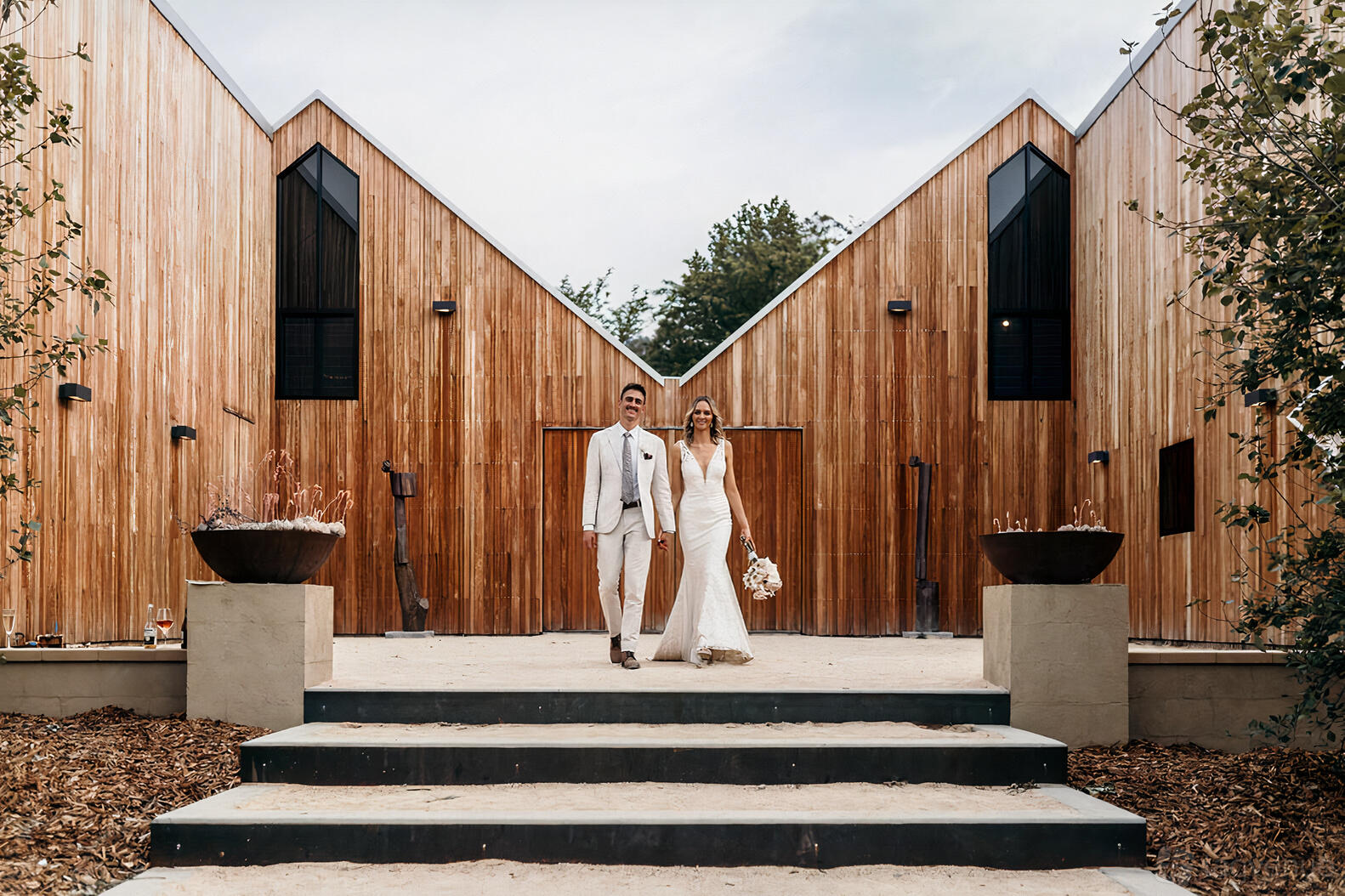A barn with timber-clad gabled exterior, large planters, and wide steps at The Woodhouse Wollombi.