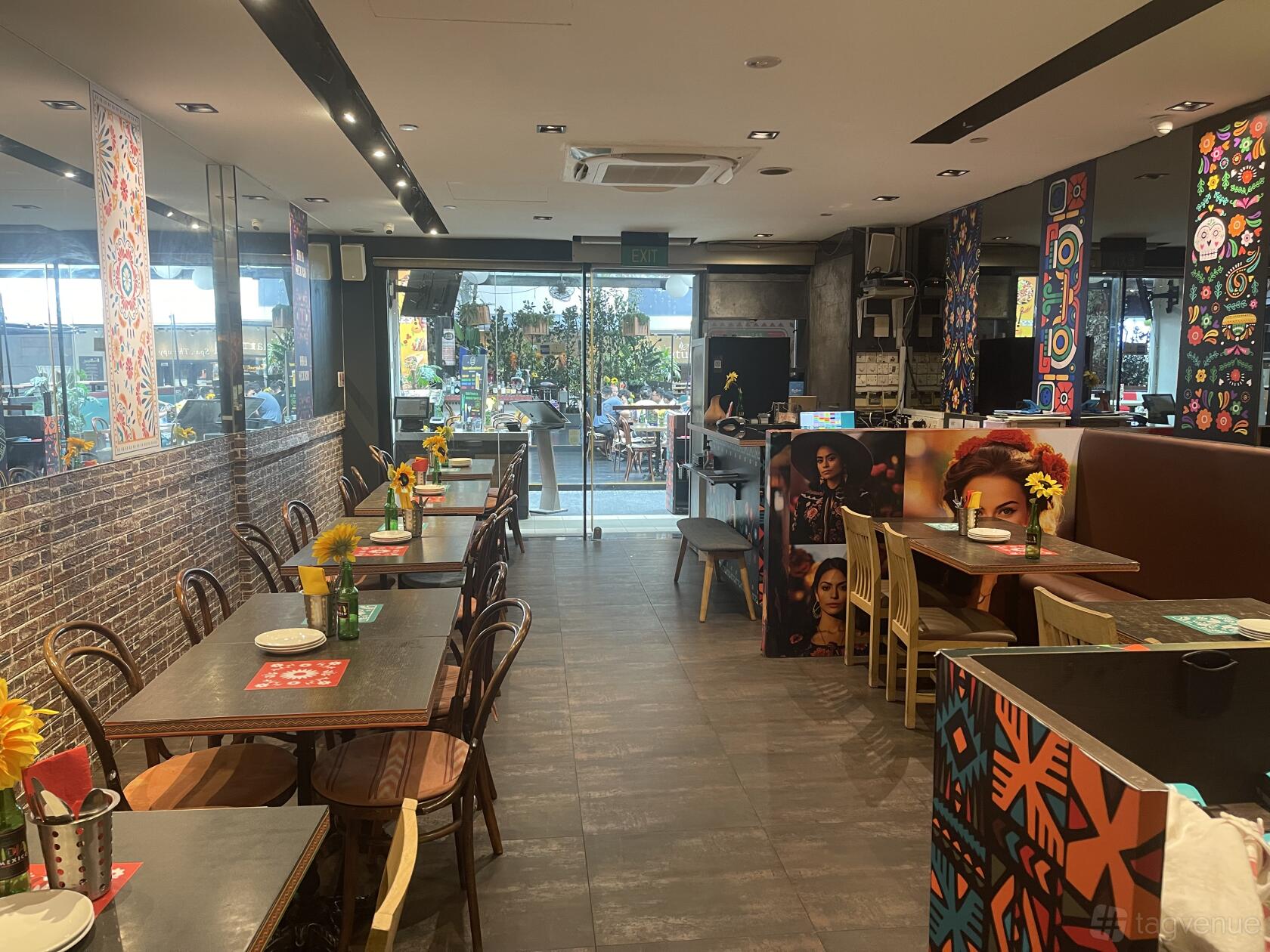 A restaurant with colorful wall art, wooden tables set with sunflowers, and an open layout at HOLA! MEXICO.