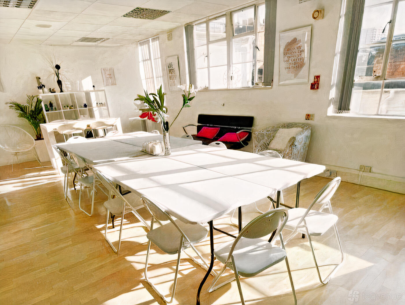 An event space with natural light, folding tables with white linens, and potted plants at Illimitable Spaces.