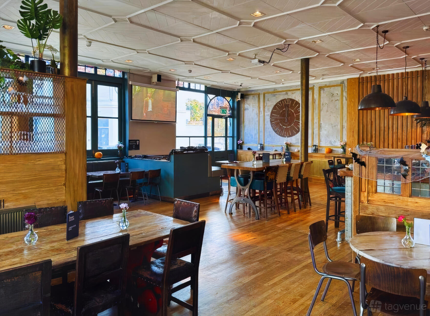 A bar with wooden floors, mixed seating, pendant lighting, and large windows at The Tommy Tucker.