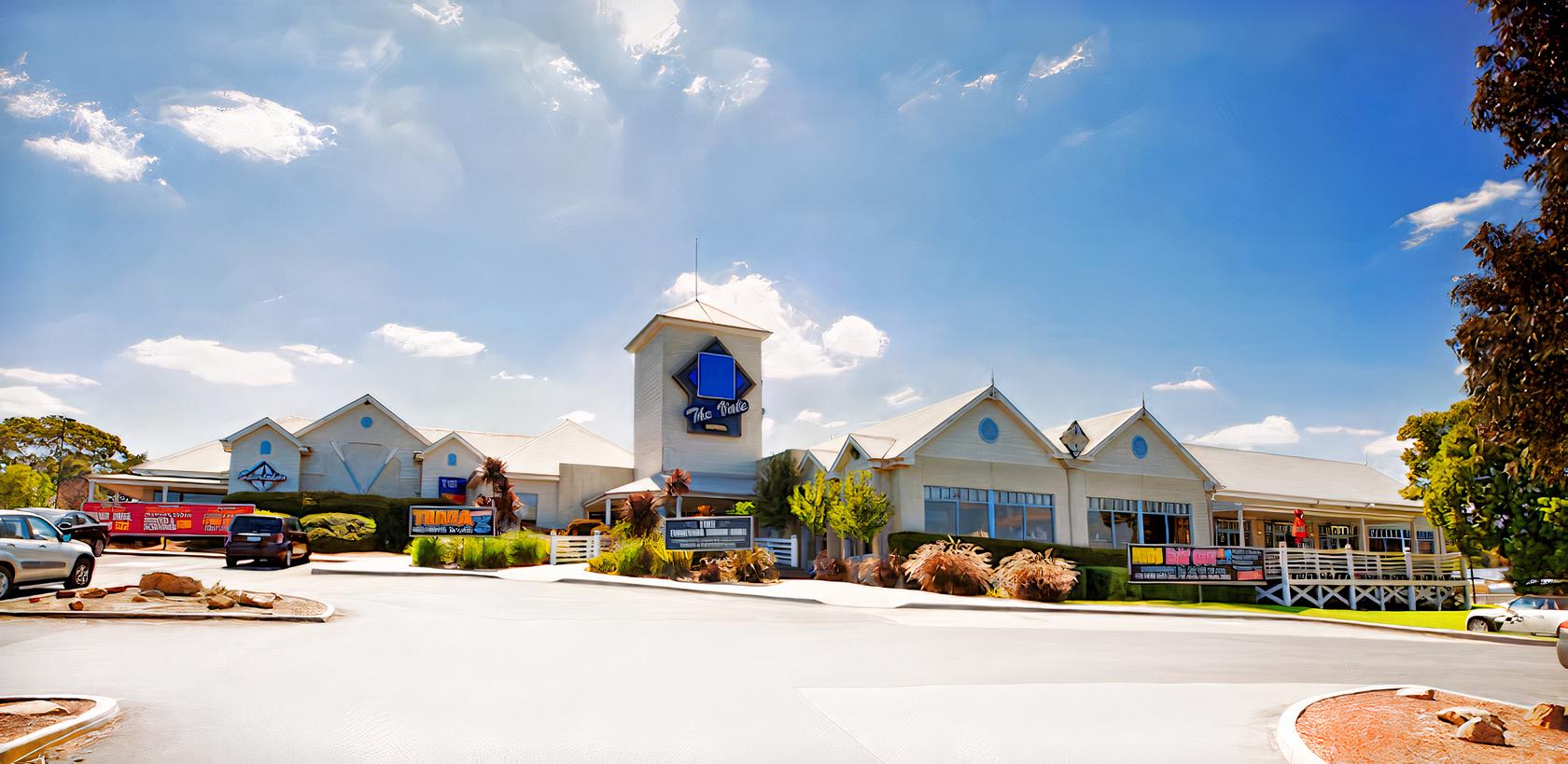 A hotel with a large tower entrance, blue signage, gable roofs, and landscaped grounds at Vale Hotel.