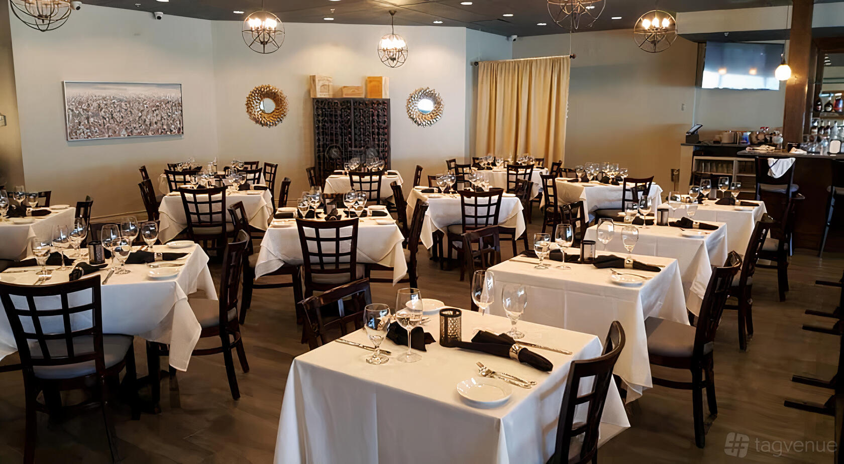 A dining room with white tablecloths, dark wooden chairs, and decorative mirrors at Scotty's on Sheridan.