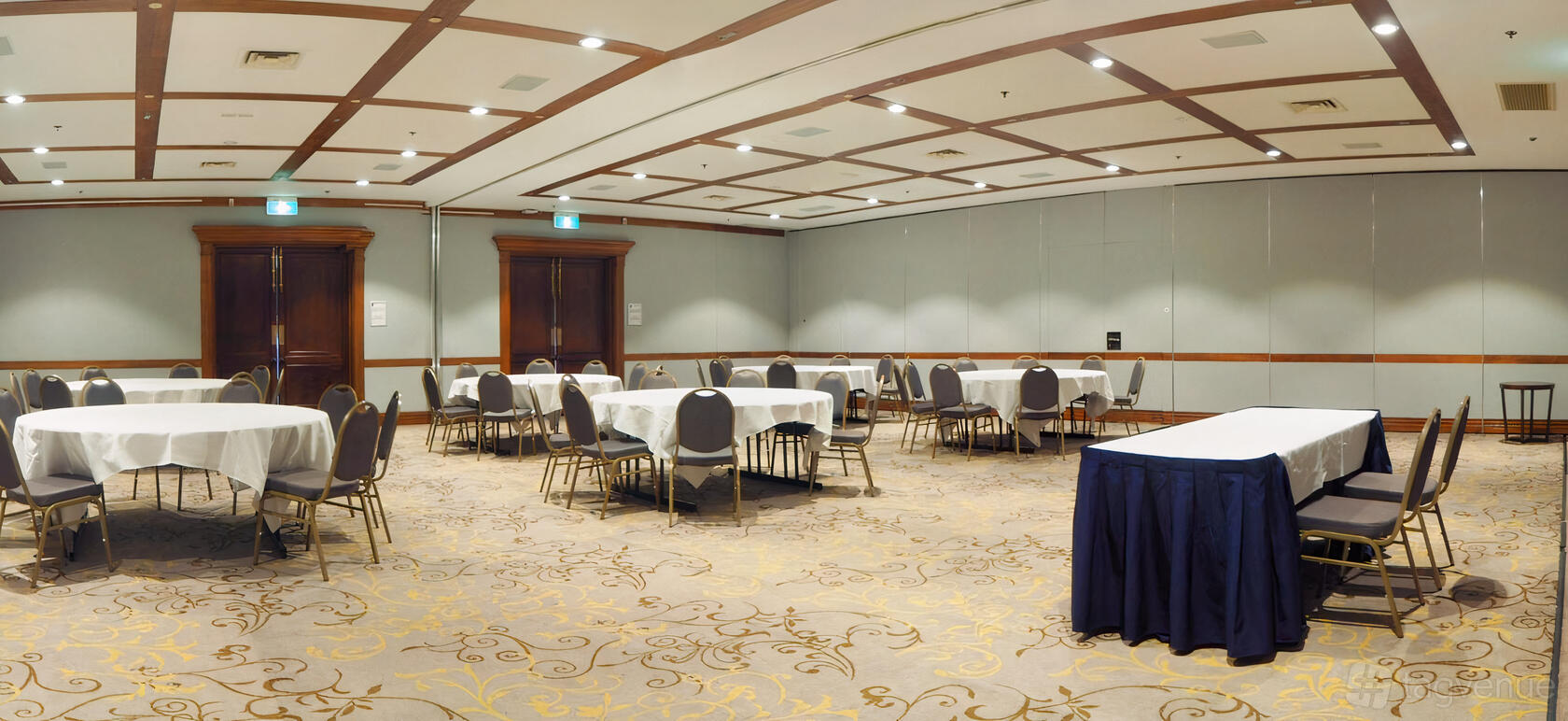An event room with patterned carpet, coffered ceiling, and round tables with white tablecloths at Fairmont Resort Blue Mountains.