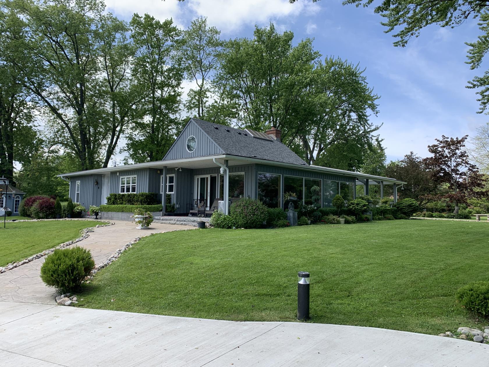 A country house event space with a wraparound porch and manicured lawn at Maison George.