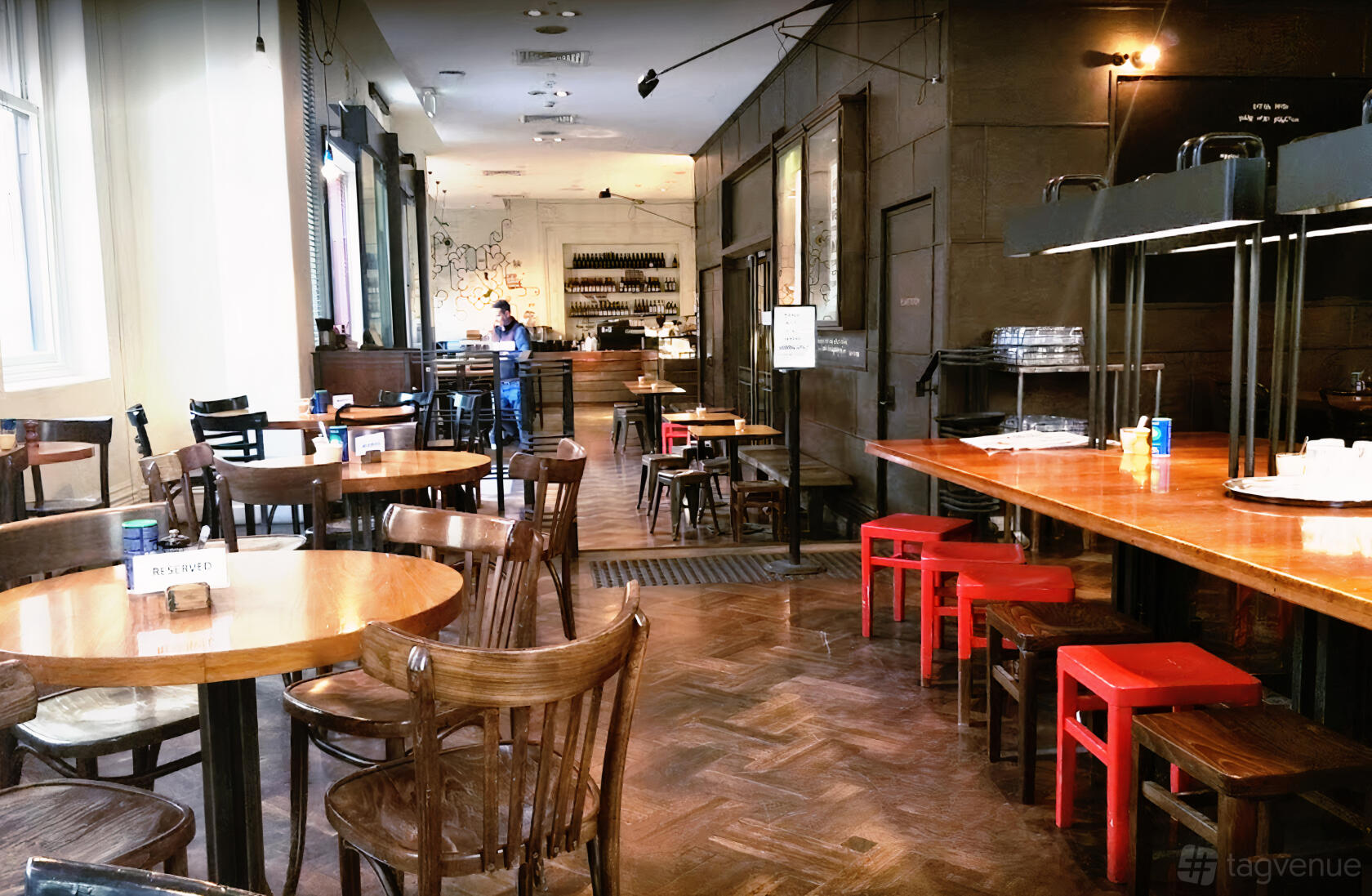 A cafe with wooden floors, mismatched wooden chairs, round tables, and large windows at Mr Tulk Cafe.