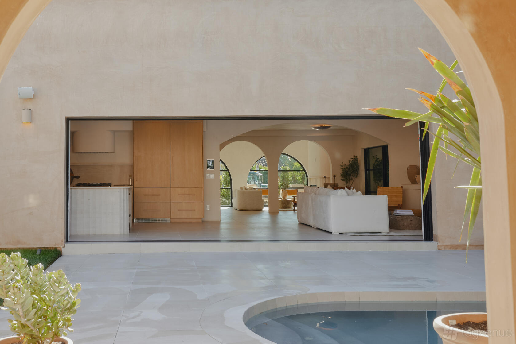 A house with arched doorways, white sofas, and an open-plan living space overlooking a pool at Casa Terracota.
