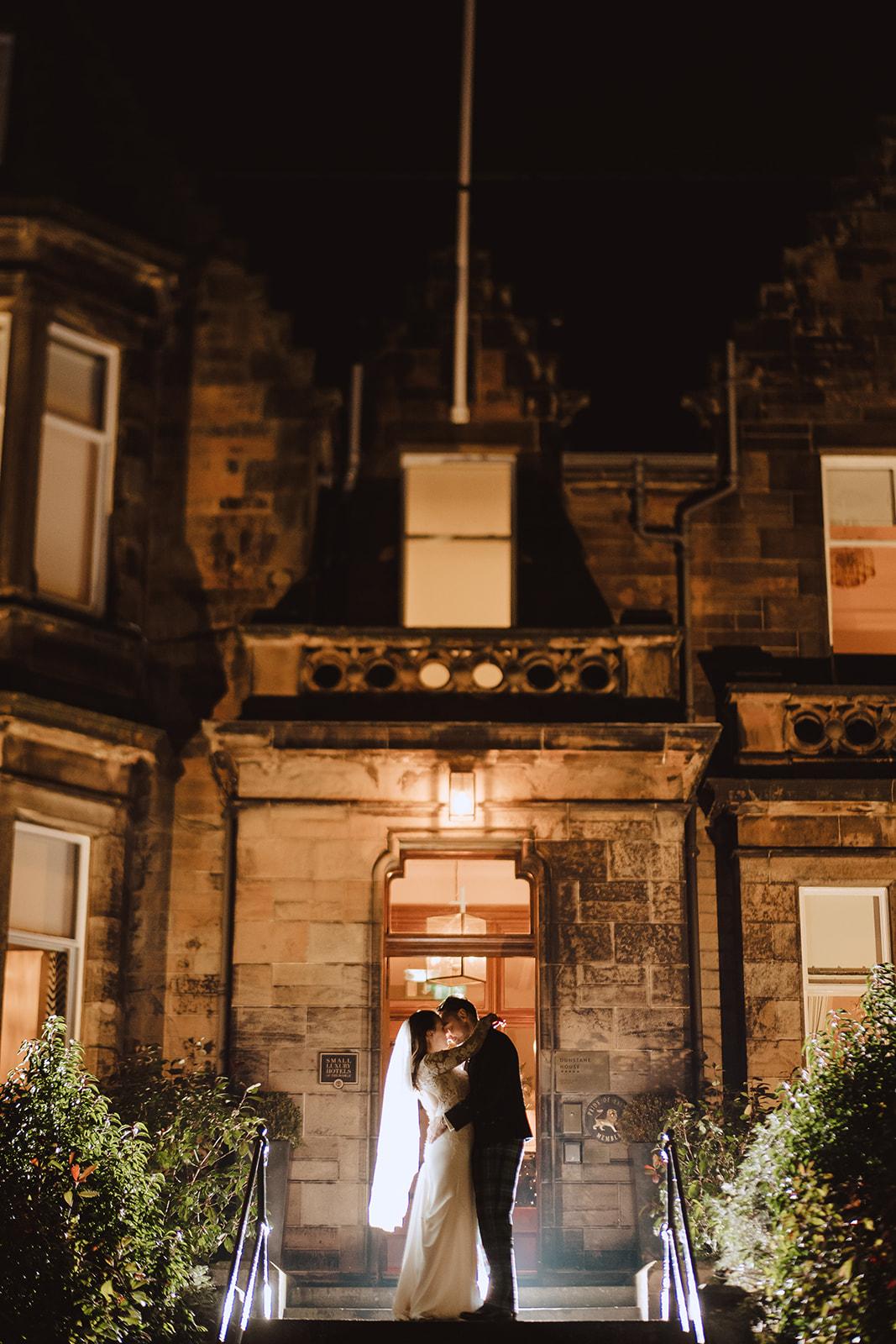 A historic hotel exterior with illuminated stone facade and large sash windows at The Roseate Edinburgh.