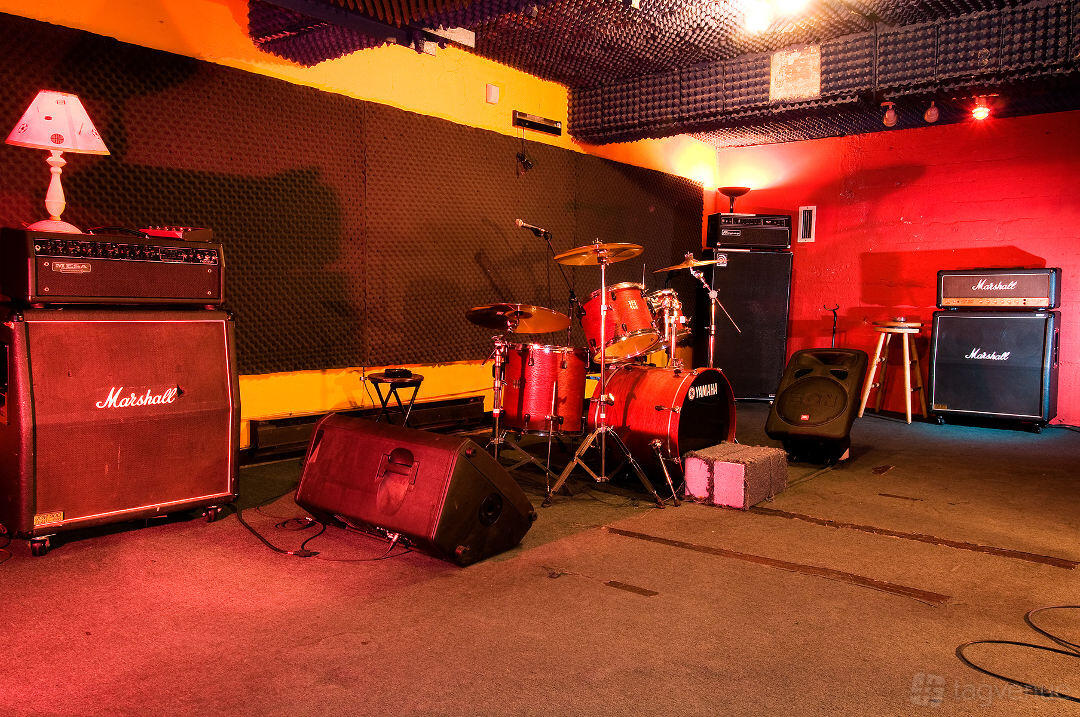 A recording studio with a drum kit, amplifiers, and soundproofed walls at The Best Deal in Town.