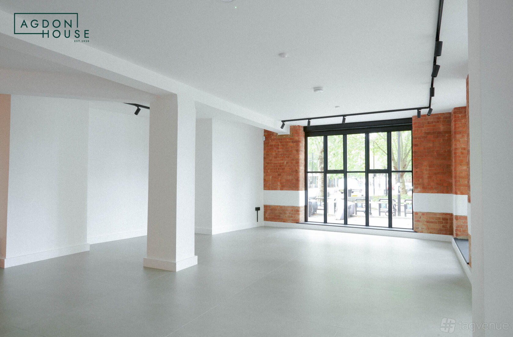 A blank canvas venue with large windows, exposed brick accents, and white walls at Agdon House.