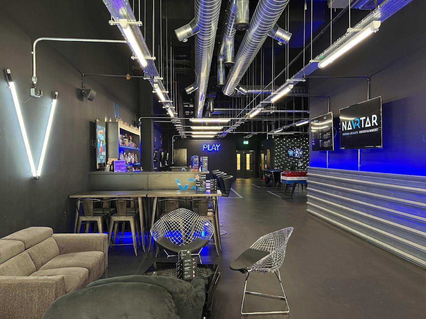 An event venue with exposed ductwork, neon lighting, a bar area, and lounge seating at Navrtar.