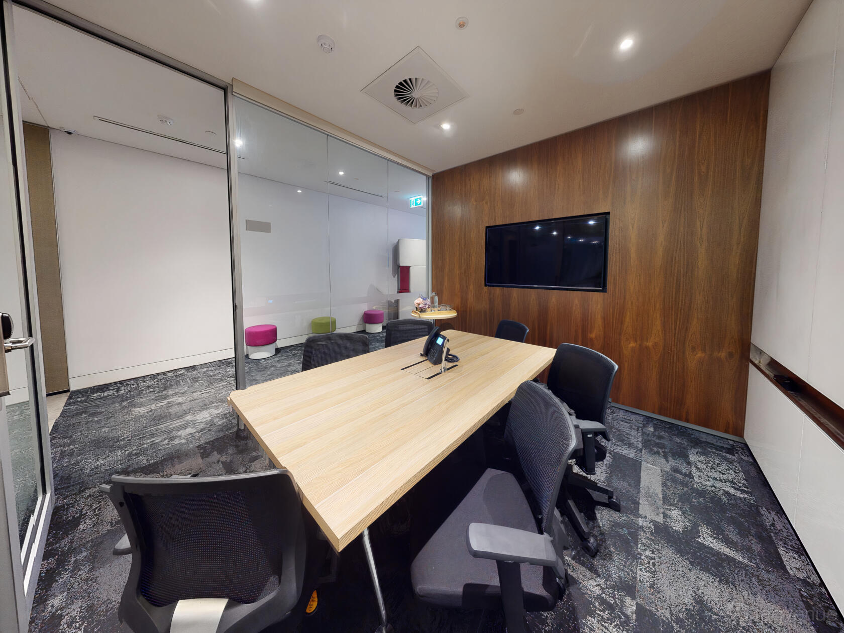 A meeting room with a light wood conference table, six chairs, wall-mounted screen, and wood paneling at Compass Offices - 9 Castlereagh Street.