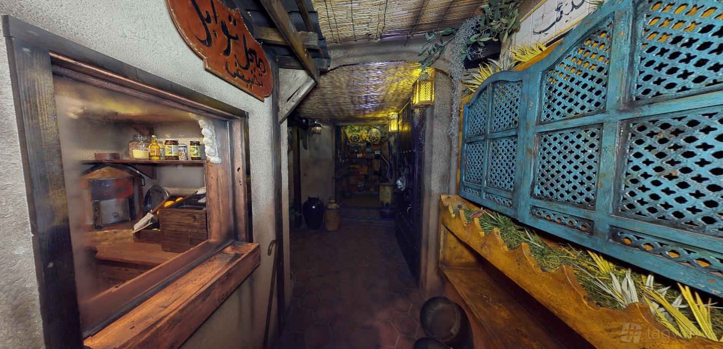An immersive event venue hallway with rustic decor, shelves of dried herbs, and market-themed props at The Escape Game Houston- The Galleria.