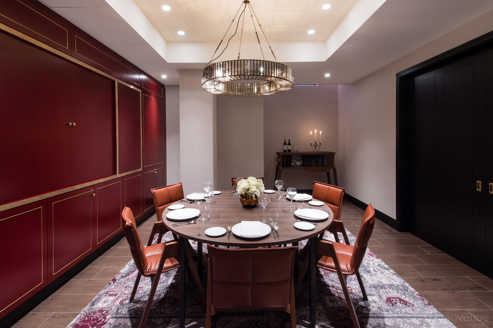 A meeting room with a round wooden table, red leather chairs, and a modern chandelier at Vintry & Mercer.