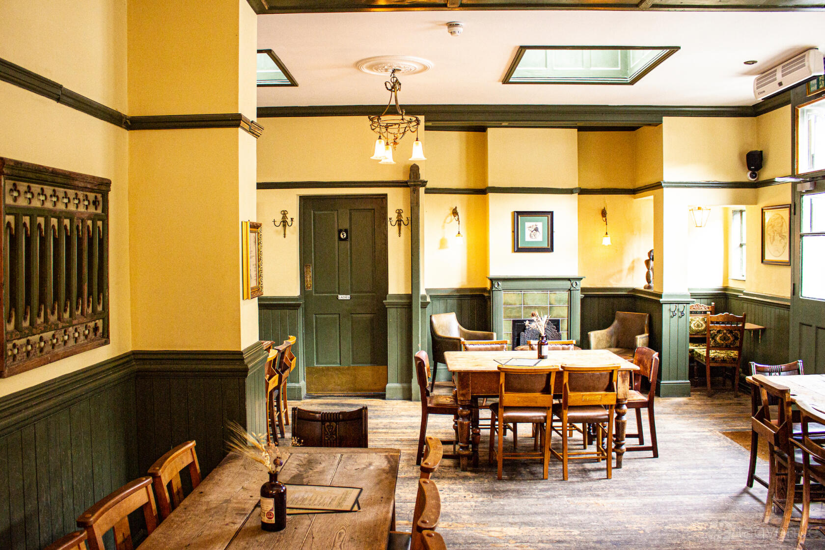 An event space in a pub with wooden tables, vintage chairs, and panelled walls at The George & Monkey.