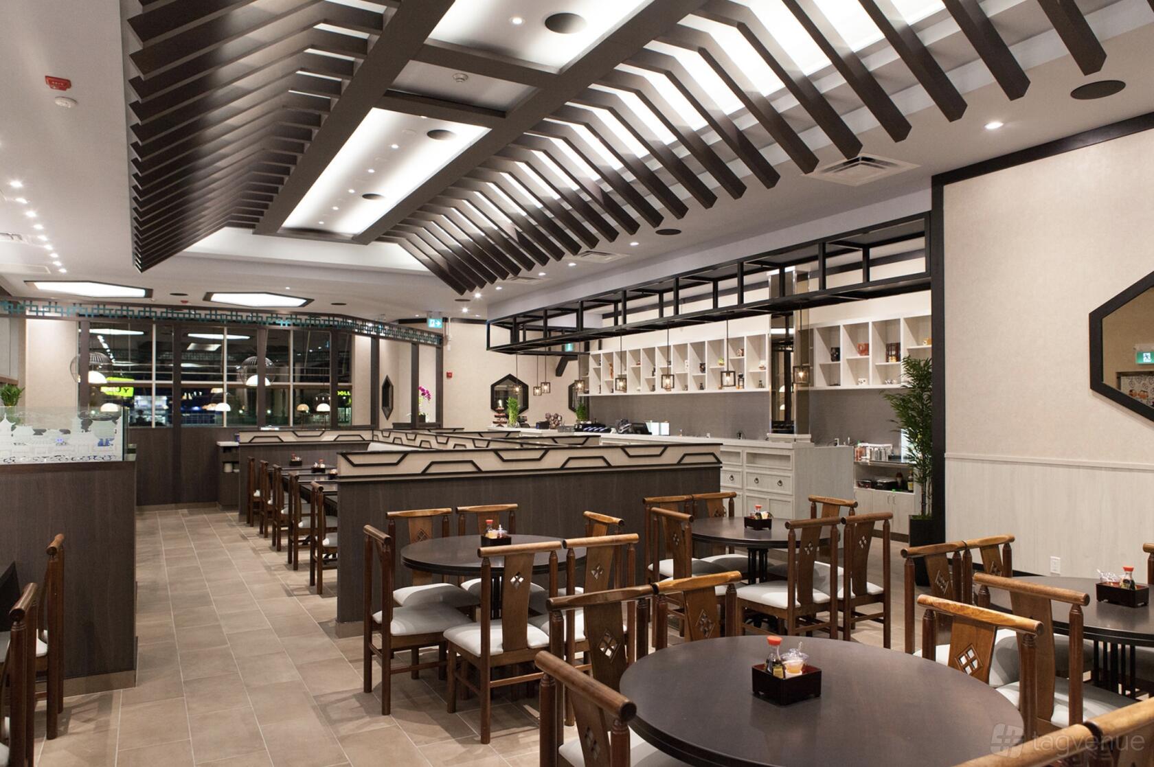 A restaurant with round dark wood tables, wooden chairs, and geometric ceiling accents at Lee Chen Asian Bistro - Aurora.