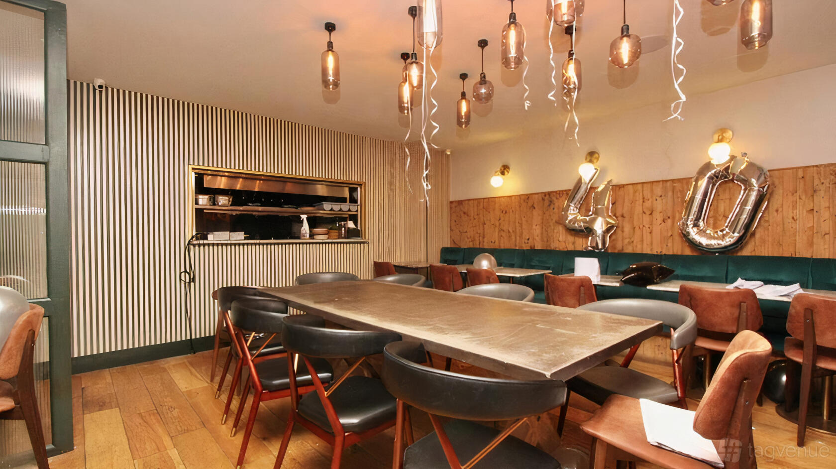 A restaurant dining area with pendant lighting, wood panel walls, and metallic balloon decorations at OCTAVES KITCHEN.