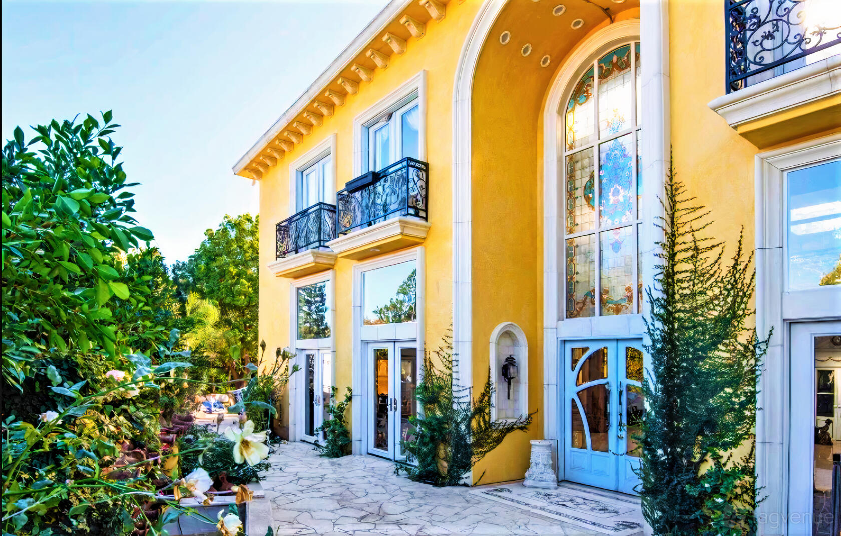 A versatile event space with tall arched stained-glass windows and a stone patio at Sunset Estate.