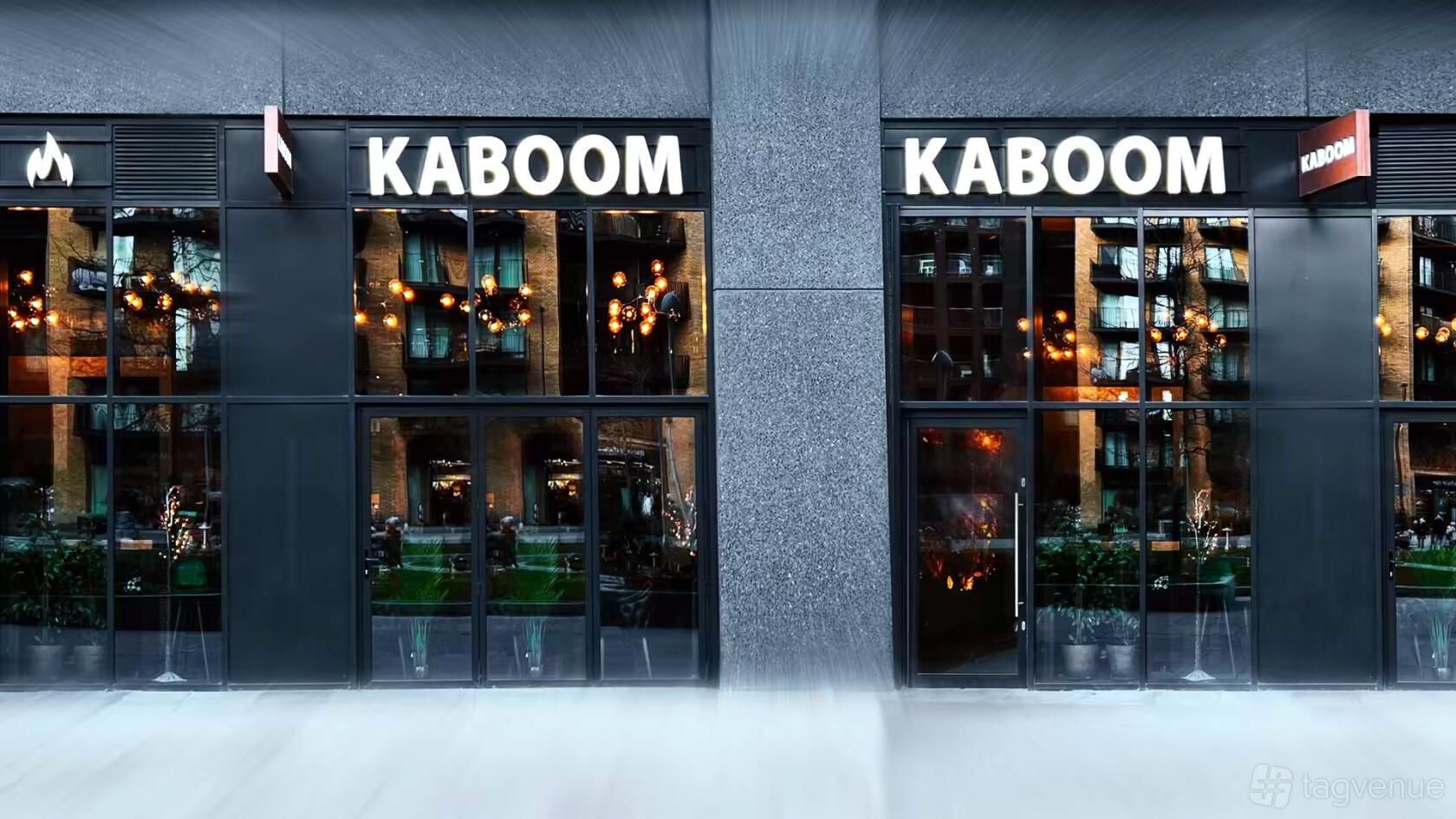 A restaurant with floor-to-ceiling windows, modern black facade, and glowing chandeliers at Kaboom Lounge & Restaurant.