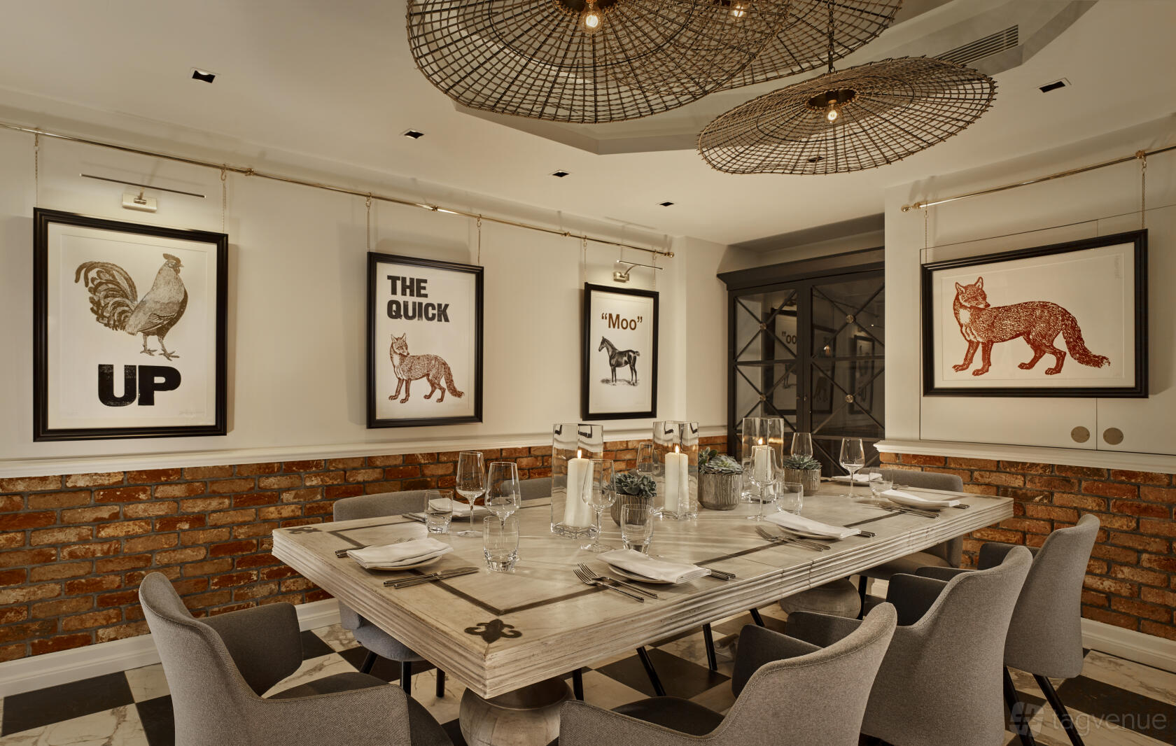 A dining room with exposed brick walls, animal artwork, and a long wooden table set for guests at The Residence at Holmes Hotel London.