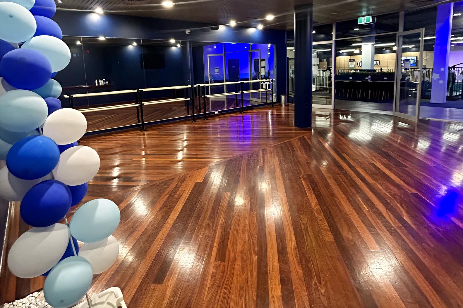 A dance studio with polished wooden floors, mirrors, and ballet barres at MyFirstGym.