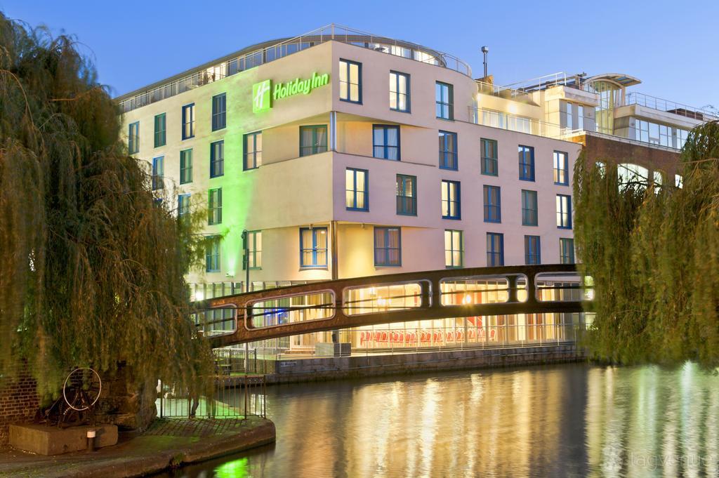 A hotel with large windows and a curved facade overlooking a canal at Glasshouse Camden.